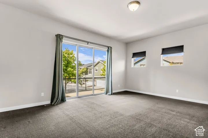 Expansive sliding glass door leading to a balcony with metal railing, accompanied by two additional windows with blinds