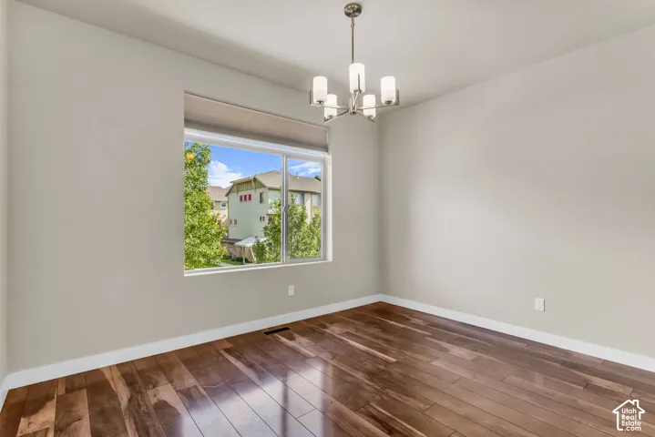 Spacious room featuring wood-finish flooring, a large window, a ceiling-mounted light fixture, and light-toned walls