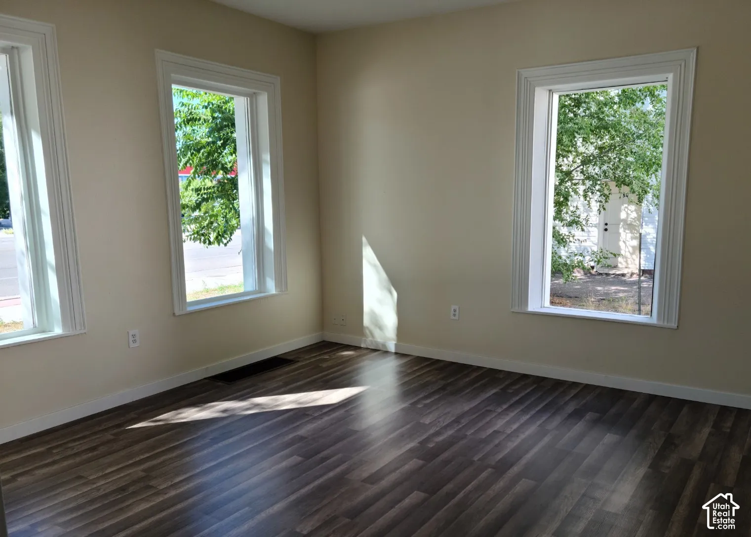 Wood-finish flooring with three large windows featuring white trim