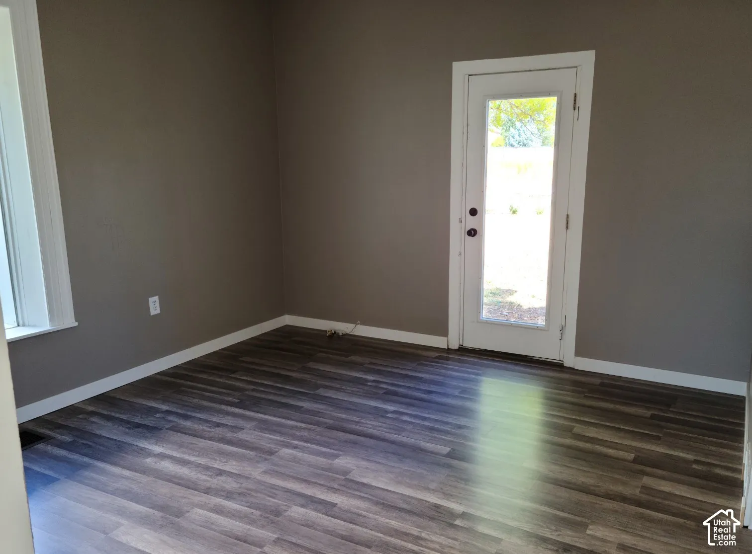 Wood-finish flooring, neutral wall paint, white trim, and a glass-paneled exterior door