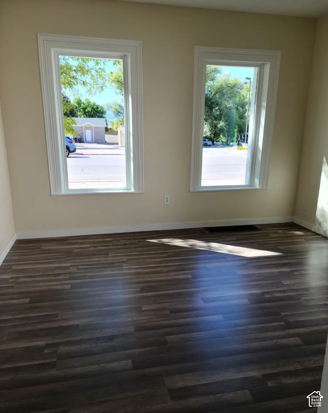 Wood-finish flooring and two windows with white trim