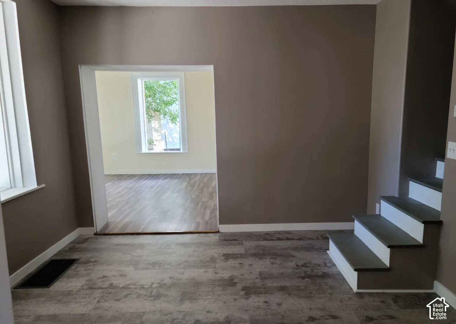 Wood-finish flooring, freshly painted walls, white trim, and a window for natural illumination