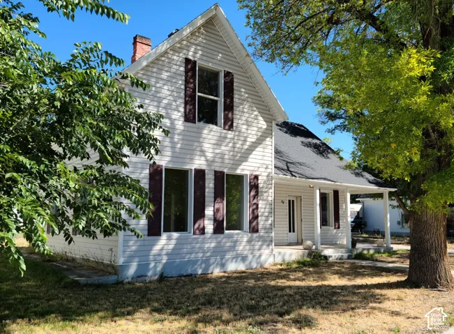White siding exterior with dark shutters, gabled roofline, and an inviting front porch