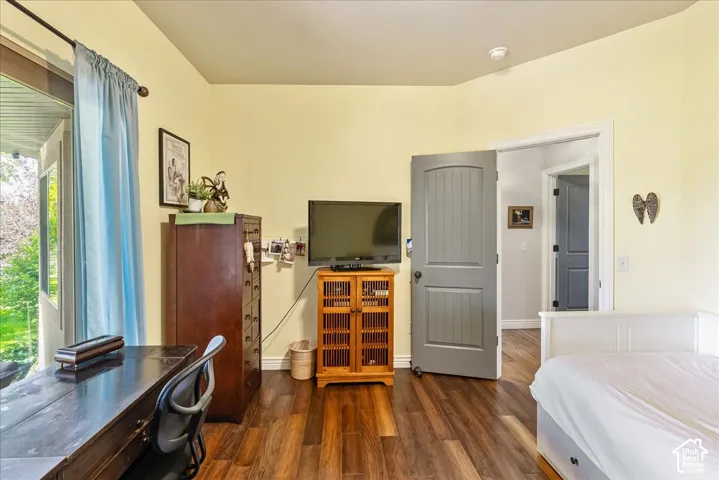 Wood-finish flooring, light yellow painted walls, white trim, and a gray interior door with black hardware