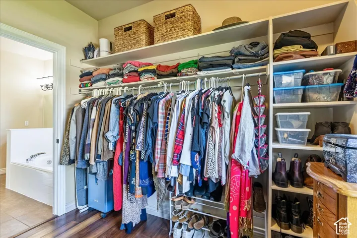 Integrated closet storage with wood-finish flooring, featuring multiple hanging rods and built-in shelving