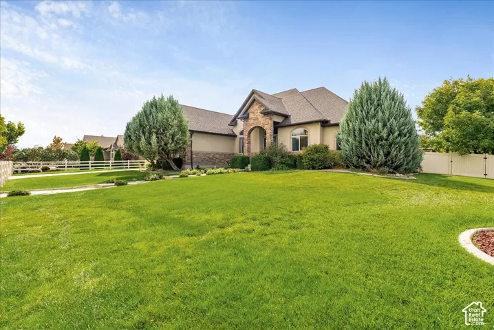 Stucco exterior with stone accents, arched entryway, gabled roofline, and manicured front yard with established landscaping