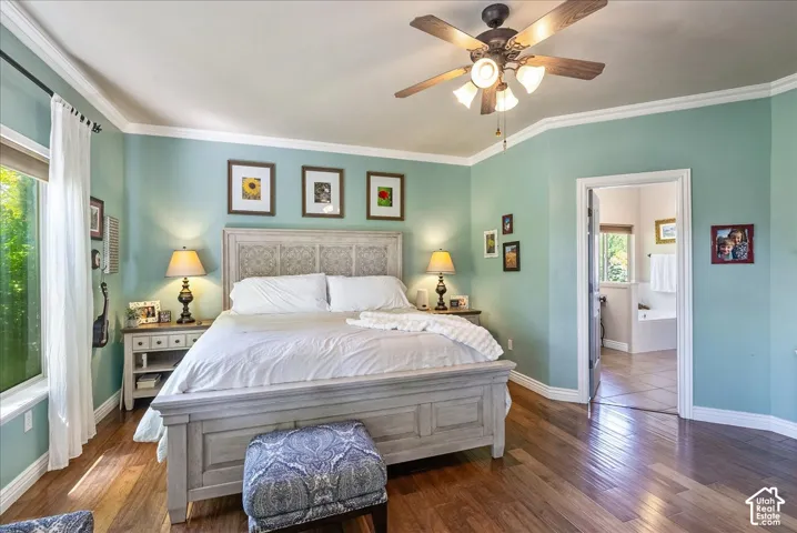 Hardwood flooring, crown molding, ceiling fan with integrated lighting, and an attached bathroom with a built-in tub