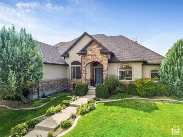 Stone and stucco exterior with an arched entryway, multiple arched windows, a multi-gabled roof, and a concrete pathway