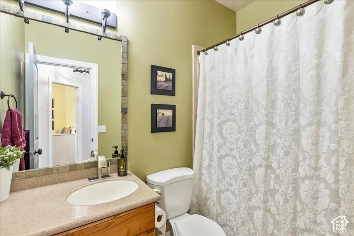 Vanity with integrated sink, wood cabinetry, and a stone-tiled mirror frame