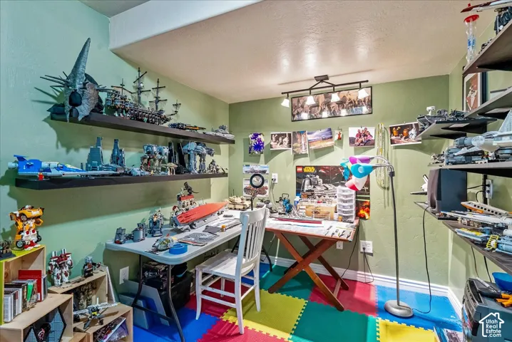 Recessed ceiling with track lighting, multiple built-in shelving units, light green wall finishes, and a colorful foam tile floor