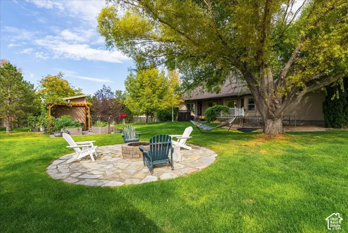 Expansive green lawn with a flagstone patio and built-in fire pit