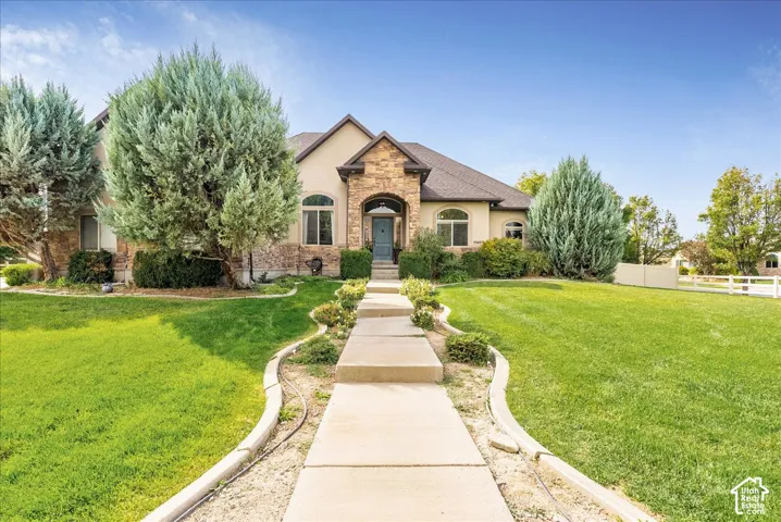 Stucco exterior with stone accents, a gabled roof, arched entry, and a concrete pathway