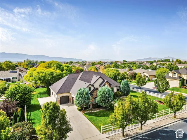 Stately residence featuring a stone and stucco exterior, an attached garage, and a long concrete driveway
