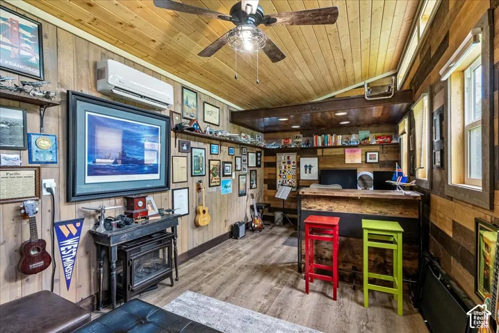 Wood-finish plank walls and ceiling, ceiling fan, built-in shelving, wood-finish flooring, and multiple windows