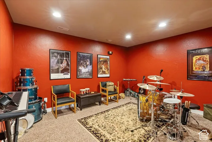 Carpeted room with recessed lighting and red-painted walls, featuring a decorative area rug