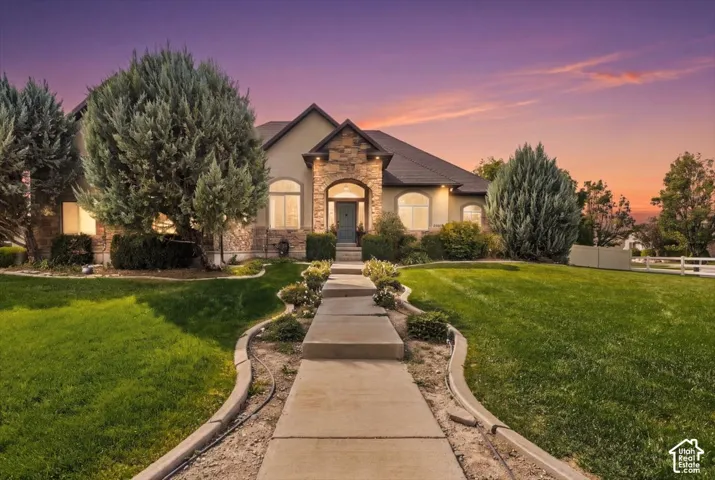 Stucco and stone exterior with arched windows, a covered entry, and a concrete pathway