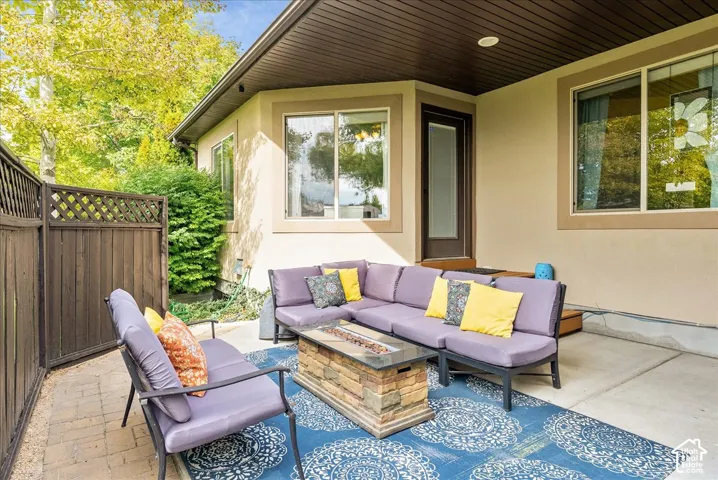 Private fenced patio with a stone fire pit, concrete flooring, and an exterior door