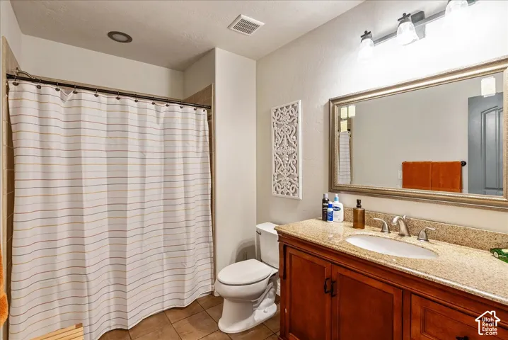 Bathroom featuring a wood-finish vanity with an undermount sink, a framed mirror, and a tile shower surround