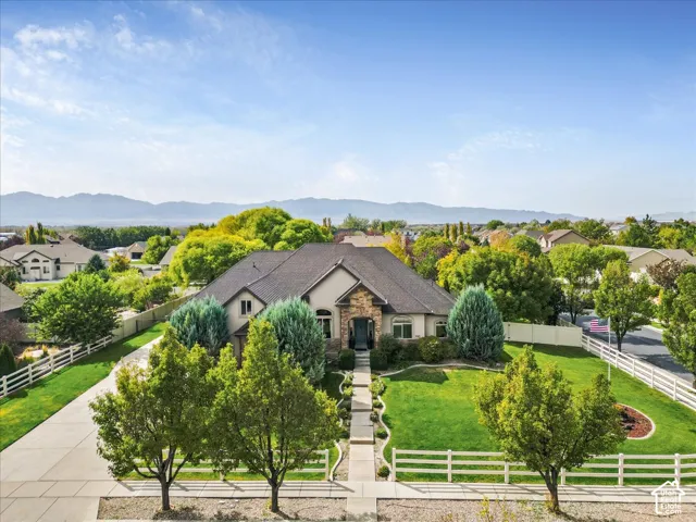Expansive landscaping with concrete driveway, stone facade detailing, and mountain backdrop