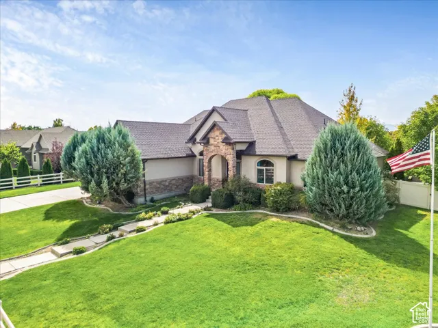 Stucco exterior with stone accents, arched entryway, and a dark shingle roof