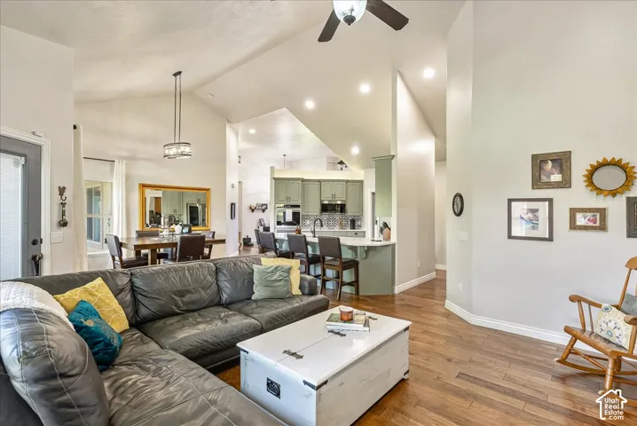 Open concept living area featuring vaulted ceilings, wood-finish flooring, recessed lighting, and a ceiling fan