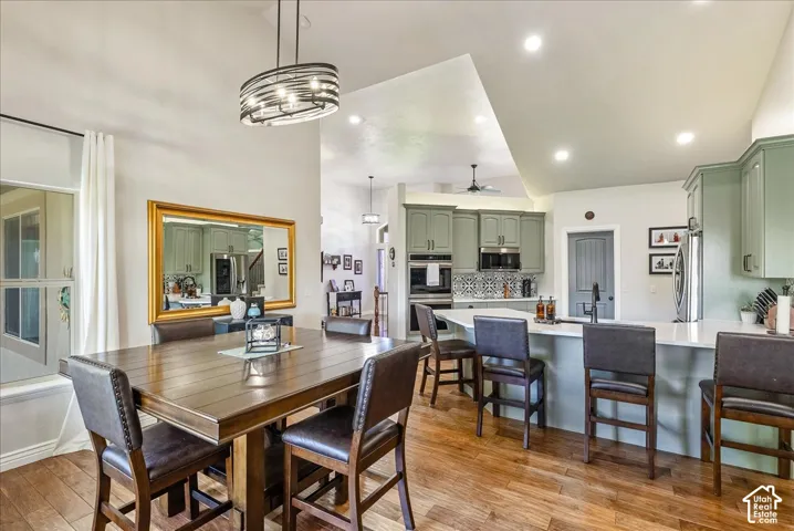 Open-concept kitchen and dining area featuring wood-finish flooring, recessed lighting, and a vaulted ceiling