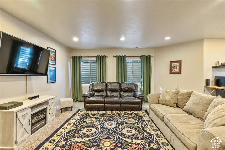 Recessed ceiling lighting, two windows with horizontal blinds, and a built-in media console with a fireplace insert