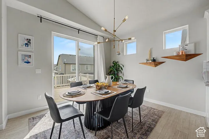 Vaulted ceiling with an exposed light fixture, wood-finish flooring, and sliding glass door