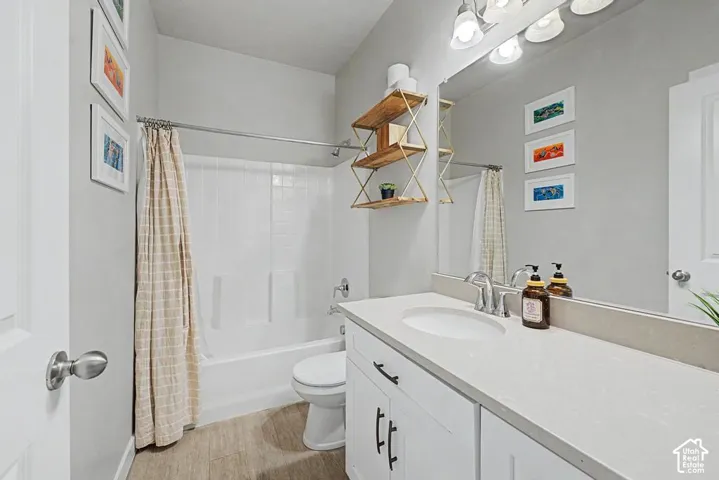 Bathroom featuring a white vanity with a light-colored countertop, an integrated sink, a full-width mirror, and a bathtub with a white tiled surround