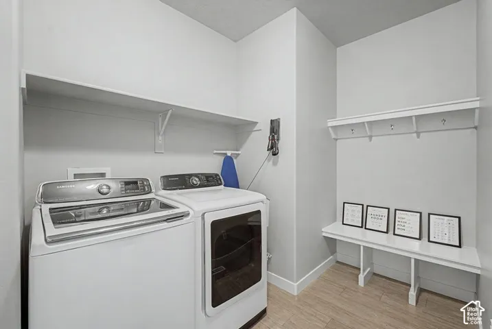 Laundry area featuring wood-finish flooring, a built-in bench, and wall-mounted shelving with hooks