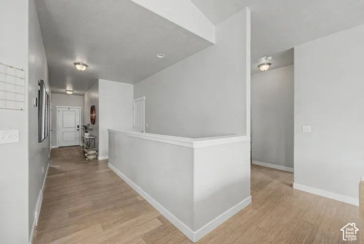 Wood-finish flooring throughout the hallway, neutral wall tones, and recessed lighting