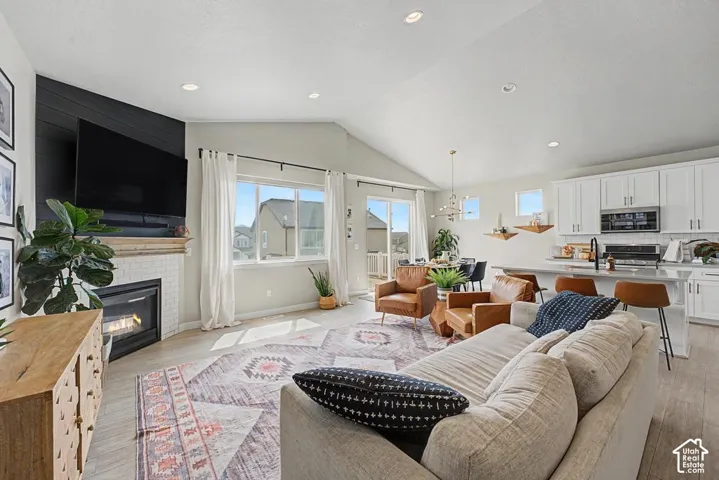 Vaulted ceilings, recessed lighting, wood-finish flooring, white shaker cabinetry, and a subway tile fireplace surround