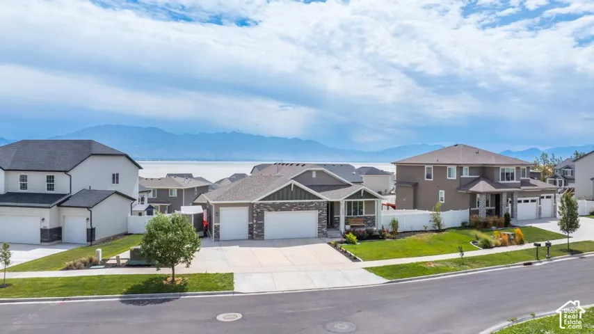 Modern residential architecture featuring a combination of siding and stone accents, concrete driveway, and attached garages