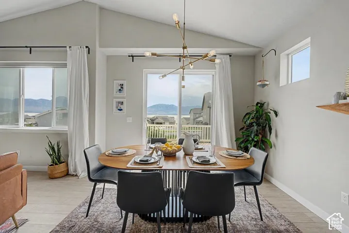 Vaulted ceiling, contemporary chandelier, sliding glass door, multiple windows, and hard-surface flooring