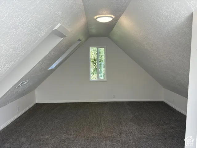 Carpeted room with sloped ceilings and a flush-mount ceiling light fixture