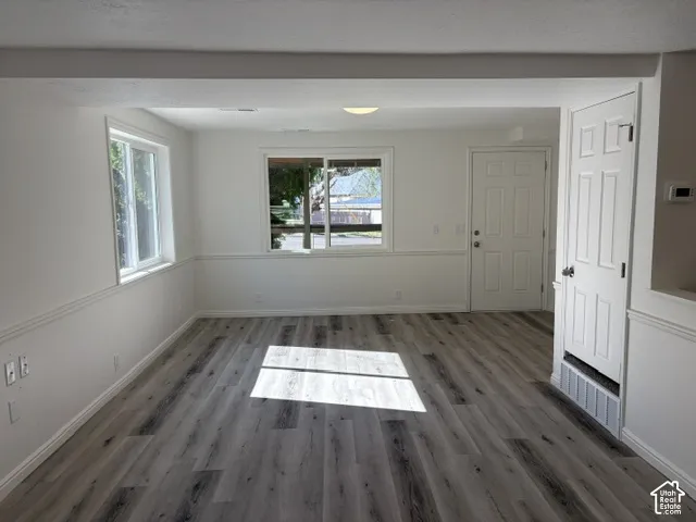 Wood-finish flooring, white walls with chair rail molding, and multiple windows