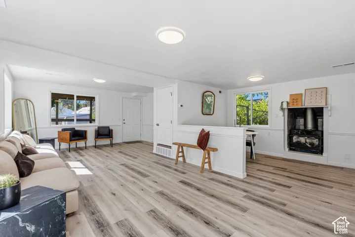 Expansive room featuring wood-finish flooring, multiple windows, a white paneled half-wall, and a built-in stove