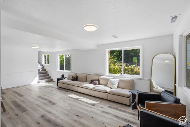 Recessed lighting, wood-finish flooring, white walls, multiple windows, and a carpeted staircase