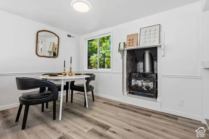 Built-in wood-burning stove with mantel, wood-finish flooring, white trim, recessed window, and ceiling light fixture
