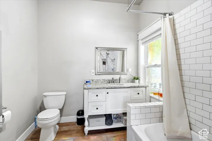 White subway tile shower surround with a built-in bench, a white vanity with drawers, a granite countertop, and a framed mirror