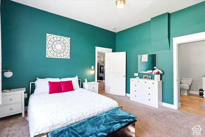 High ceilings with a flush mount light fixture, teal wall color, white trim, and a doorway opening to a bathroom with wood-finish flooring