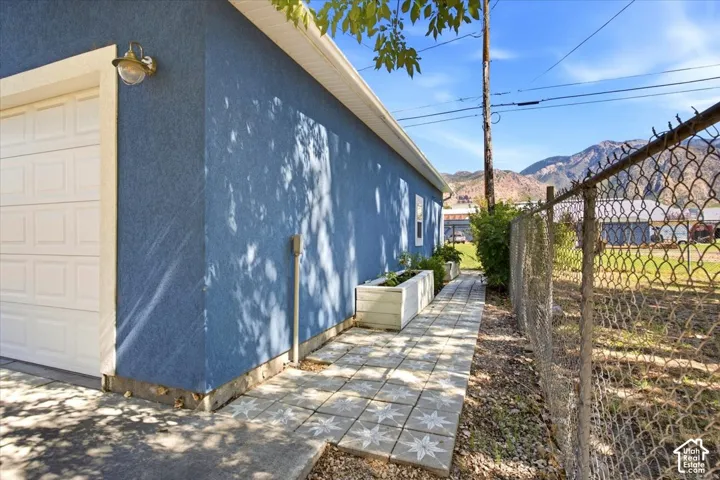 Textured blue exterior with white trim, a decorative exterior light fixture, and a white paneled garage door