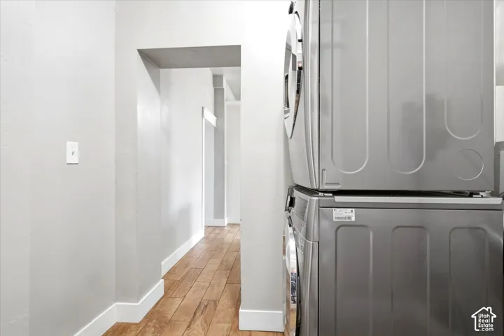 Stacked laundry appliances with a light wall finish and wood-finish flooring