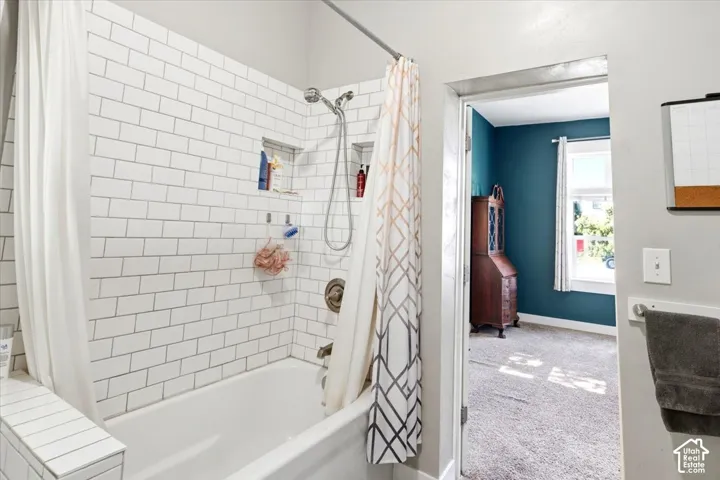 Bathtub with white subway tile surround, integrated shower niches, and a wall-mounted showerhead with handheld attachment