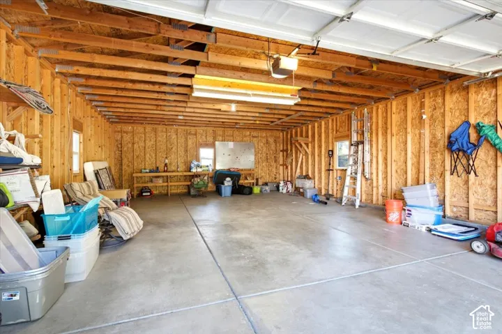 Expansive garage space with exposed wood framing, concrete flooring, and an overhead garage door