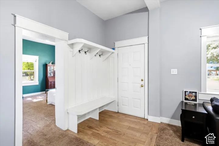 White built-in hall tree with bench, wood-finish flooring, and light gray wall paint