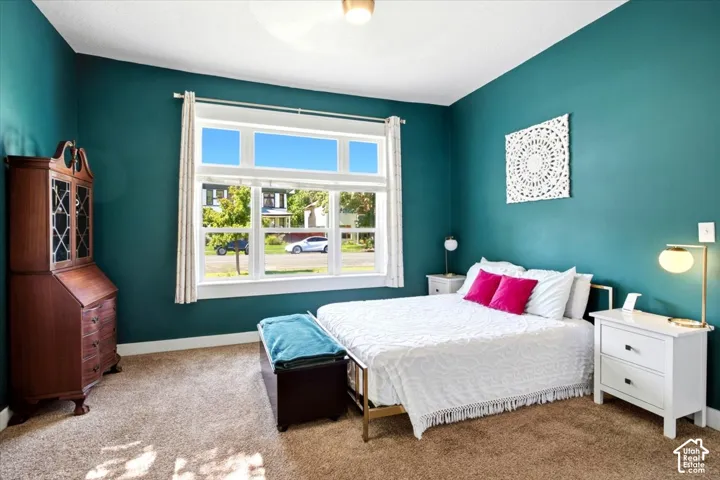 Bright bedroom with a large multi-pane window, carpet flooring, and a ceiling-mounted light fixture