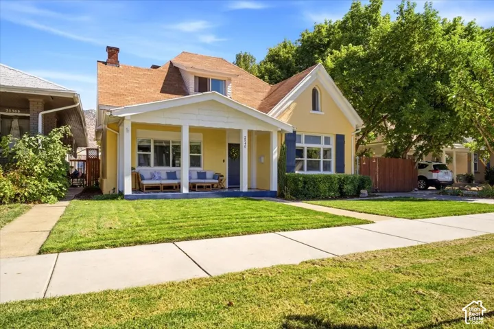 Front facade featuring a covered porch with white columns, yellow siding, and a gabled roof