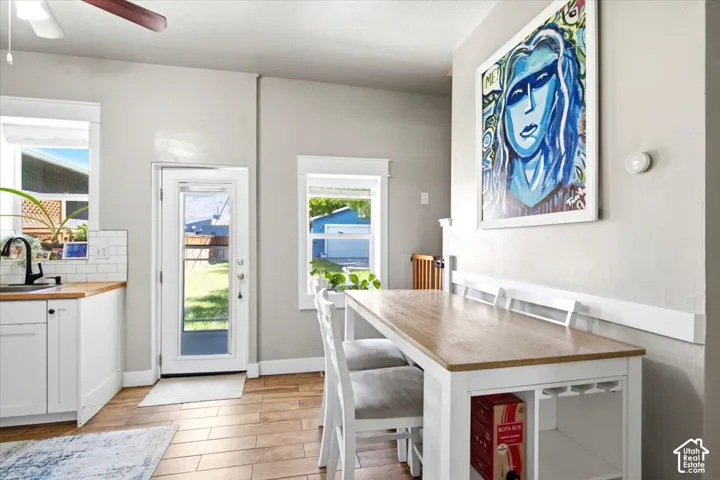 Wood-finish flooring, white cabinetry, and a subway tile backsplash