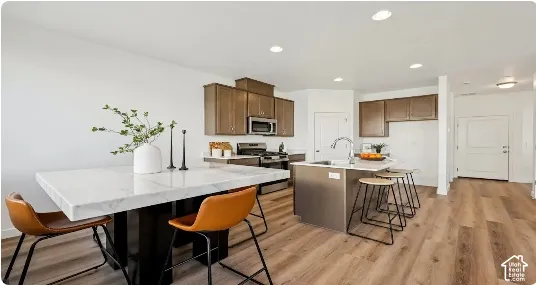Kitchen featuring wood-finish flooring, recessed lighting, and a kitchen island with a single-basin sink. This home is under construction. Pictures are of a similar home.